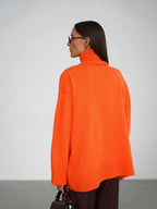 Back view of a woman wearing an oversized bright orange turtleneck sweater.