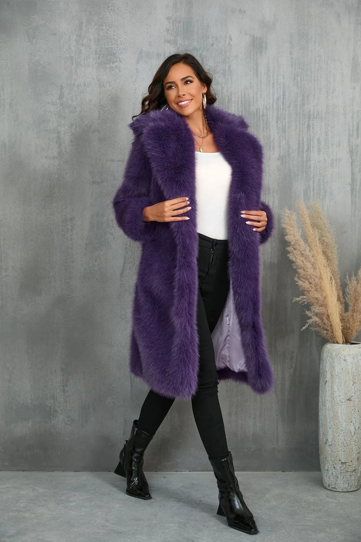 Woman smiling while wearing a purple faux fur coat and black pants