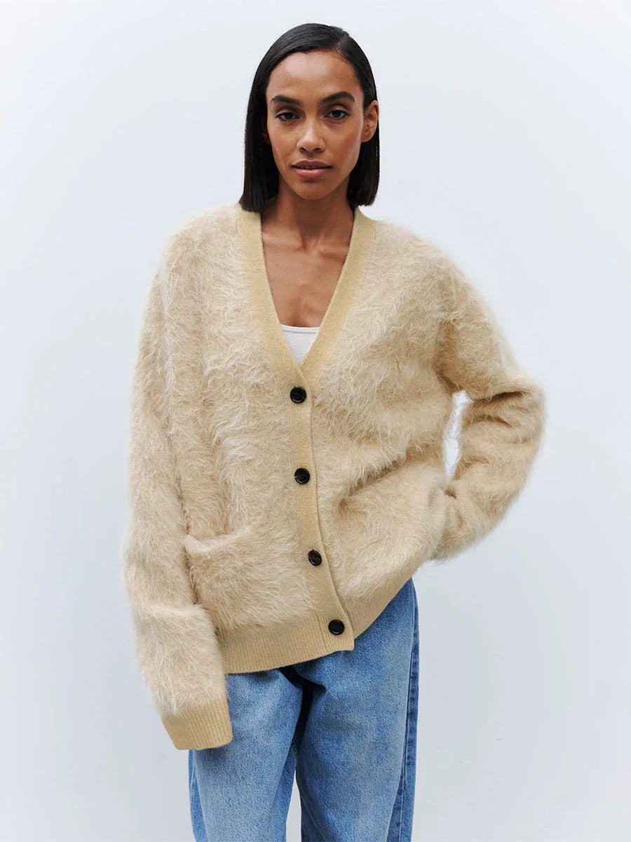 Woman wearing a beige fuzzy V-neck button-up cardigan with two front pockets and blue jeans. Main image
