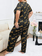 Woman wearing a black and gold "love" and heart print pajama set from the back.