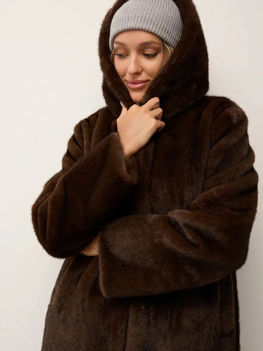 Close-up of a woman adjusting the hood of a brown faux fur coat.