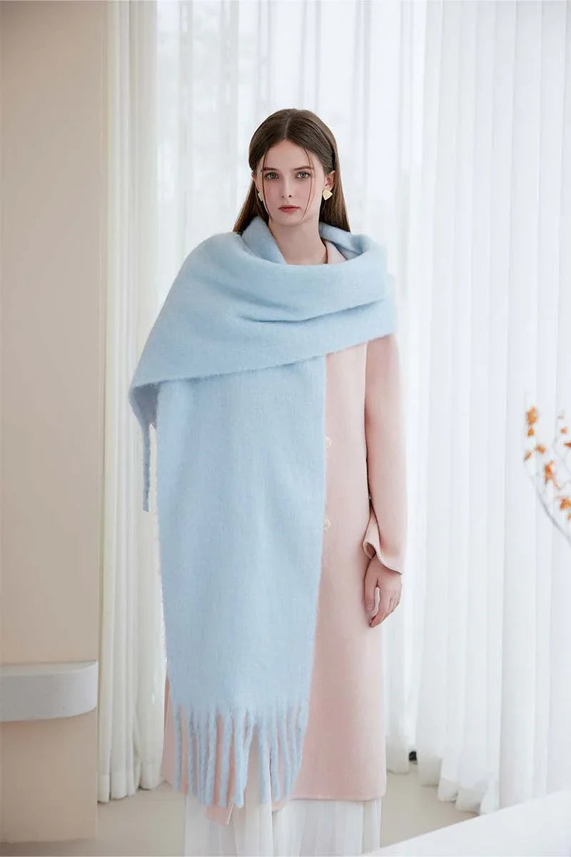 Full body shot of a woman wearing a light blue oversized mohair blend scarf with fringe.