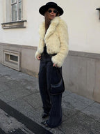 Model wearing a cream faux fur jacket with a black hat and dark jeans.