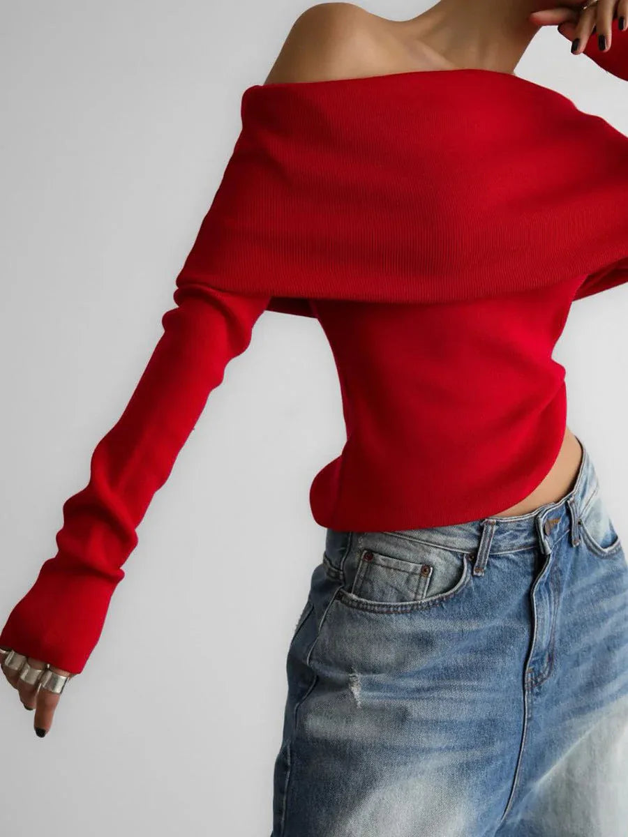 Woman wearing a red off-the-shoulder long-sleeved sweater with blue jeans, hands in front.