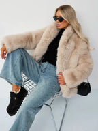 Woman sitting in a chair wearing a beige faux fur jacket and blue jeans