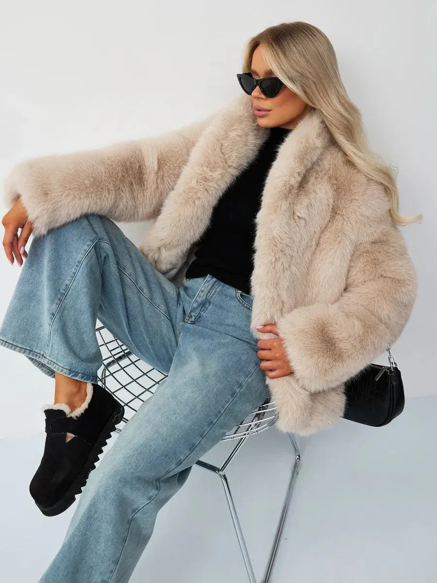 Woman sitting in a chair wearing a beige faux fur jacket and blue jeans