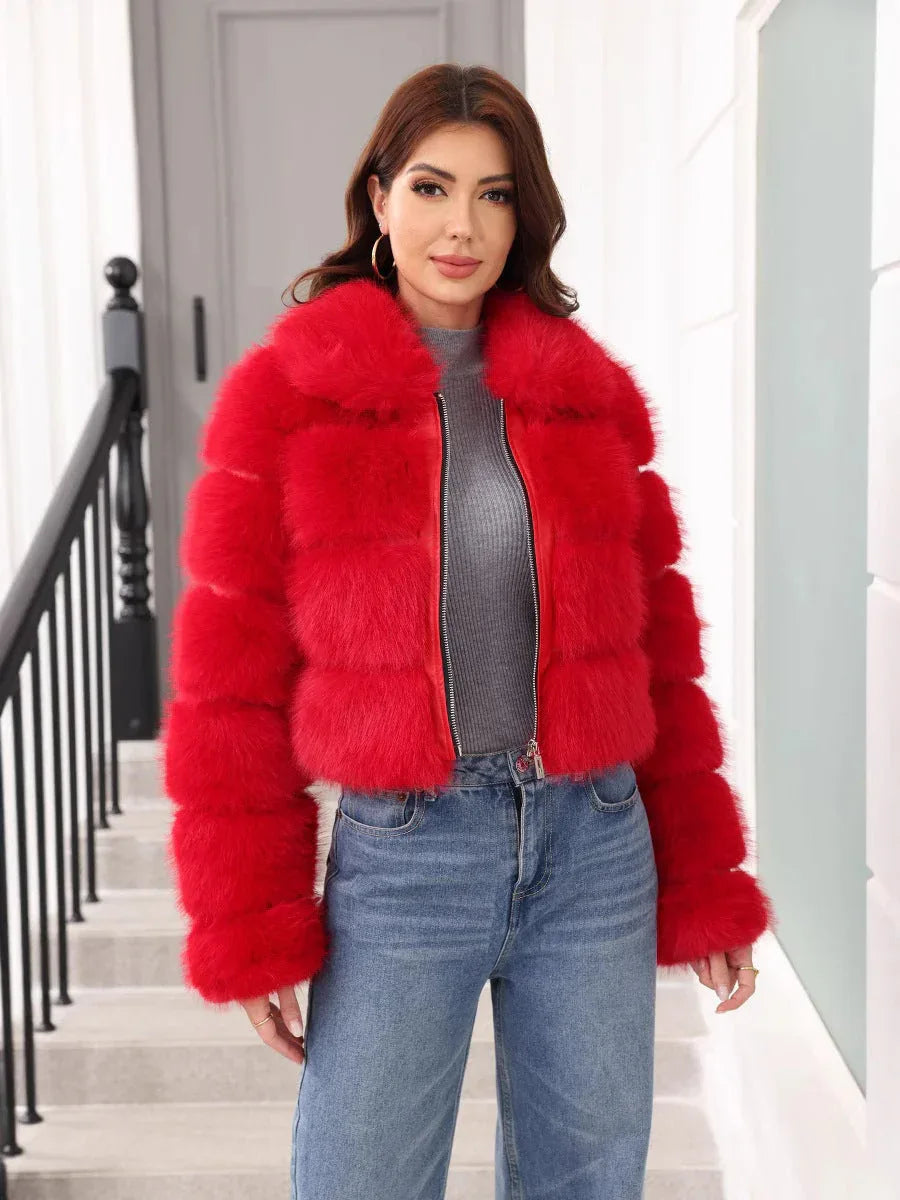 Woman wearing a red faux fur cropped jacket with a grey turtleneck and blue jeans, standing on stairs. Main image