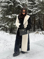 Woman in a stylish black and white striped faux fur coat, holding a black handbag in a winter setting.