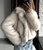 Detail of the cream faux fur cropped jacket and light wash wide-leg jeans worn by a woman taking a mirror selfie.
