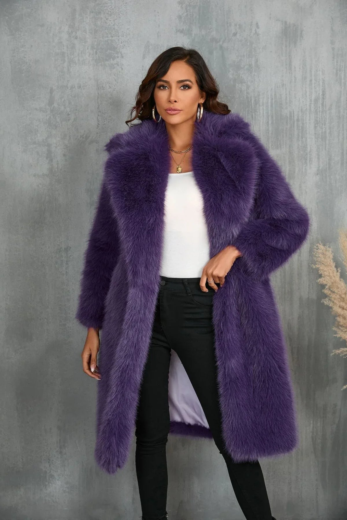 Woman wearing a long purple faux fur coat with a white top and black pants Main image