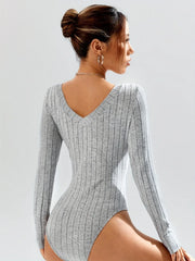 Rear view of a woman wearing a grey ribbed long-sleeve bodysuit, showcasing the V-shaped back.
