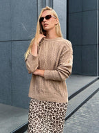 Close-up of a woman wearing a tan cable knit sweater with button details and a leopard print maxi skirt.