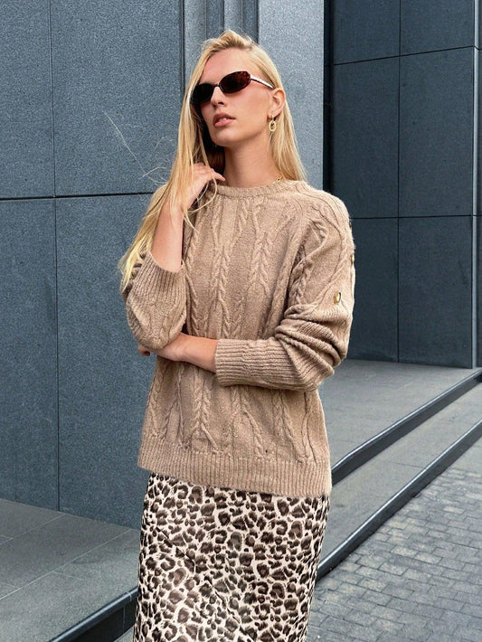 Close-up of a woman wearing a tan cable knit sweater with button details and a leopard print maxi skirt.