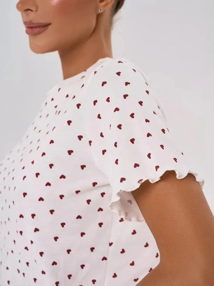 Close-up of the sleeve of a white t-shirt with a red heart print and ruffled trim.