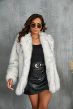 Woman wearing a white and grey faux fur coat, black top, and black leather skirt, looking at the camera.