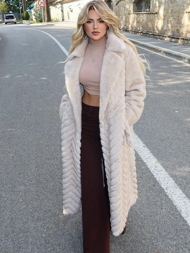 Woman wearing a cream faux fur long coat with a chevron pattern, tan crop top, and brown maxi skirt, standing on a street. Main image