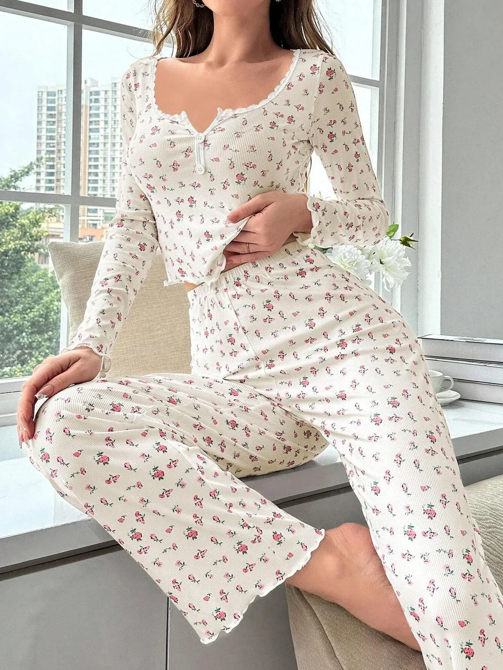 Woman sitting on a windowsill wearing a floral print pajama set