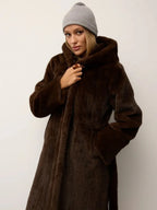 Woman wearing a brown hooded faux fur coat with a grey beanie.