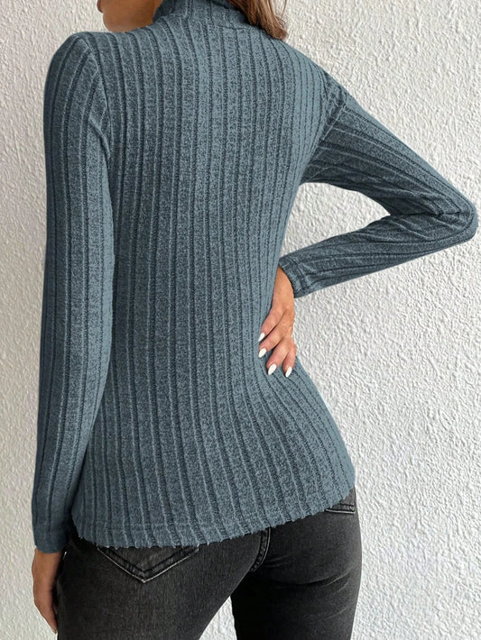 Back view of a woman wearing a fitted, long-sleeved, ribbed mock neck top in a blue-grey color with black jeans.