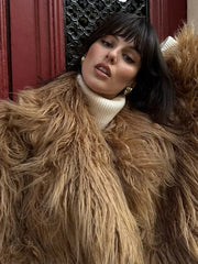 close-up of a woman wearing a shaggy brown faux fur coat and a white turtleneck