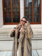 Fashionable woman in a statement faux fur coat, styled with sunglasses and a small handbag.
