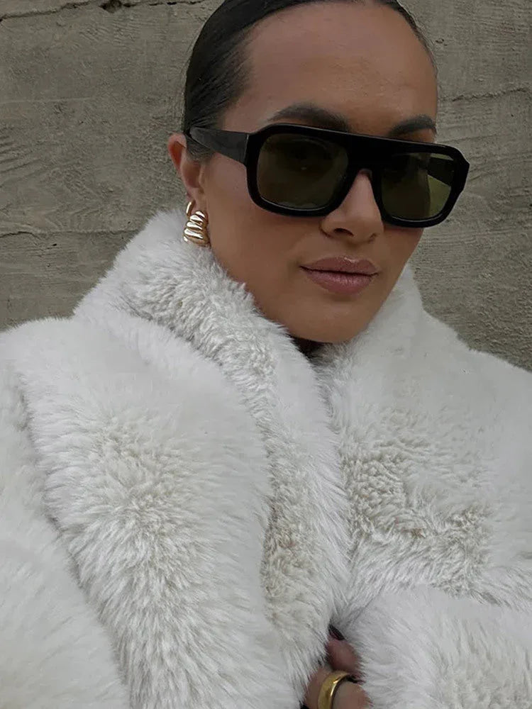 close-up of a woman wearing a white faux fur jacket and sunglasses