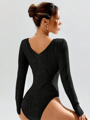 Rear view of a woman wearing a black ribbed long-sleeve bodysuit, showcasing the V-shaped back.
