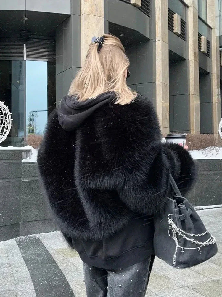 Back view of a woman wearing a black faux fur jacket and studded jeans, carrying a handbag