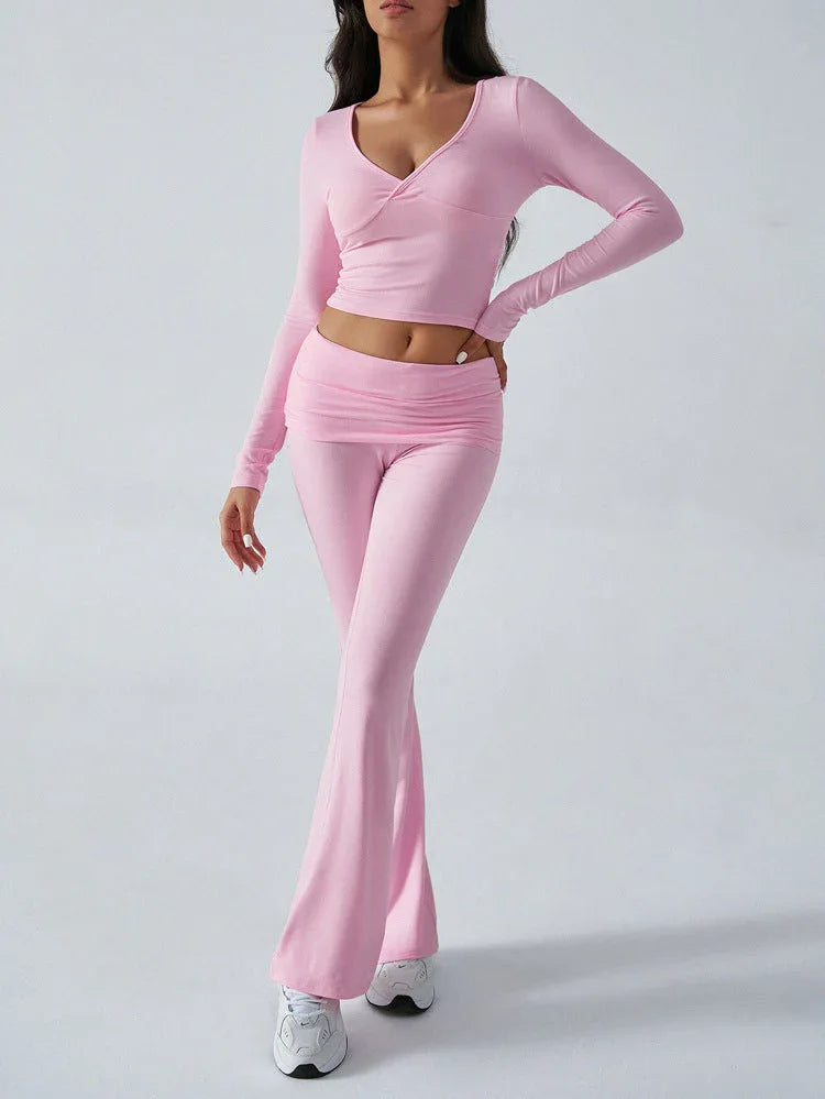 Full body view of a woman in a pink two-piece set, featuring a cropped top and flared pants