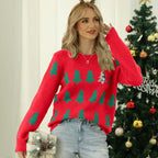 Woman wearing a red Christmas sweater with green trees and a sequined tree, holding a gift.