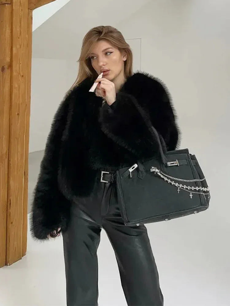 Woman wearing a black faux fur jacket with leather pants and a handbag Main image