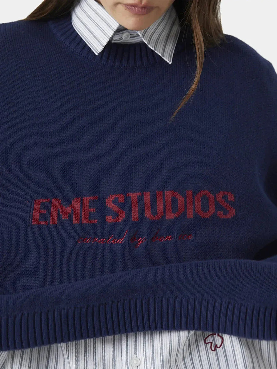 close-up of the navy blue crew neck sweater with red "EME STUDIOS" embroidery