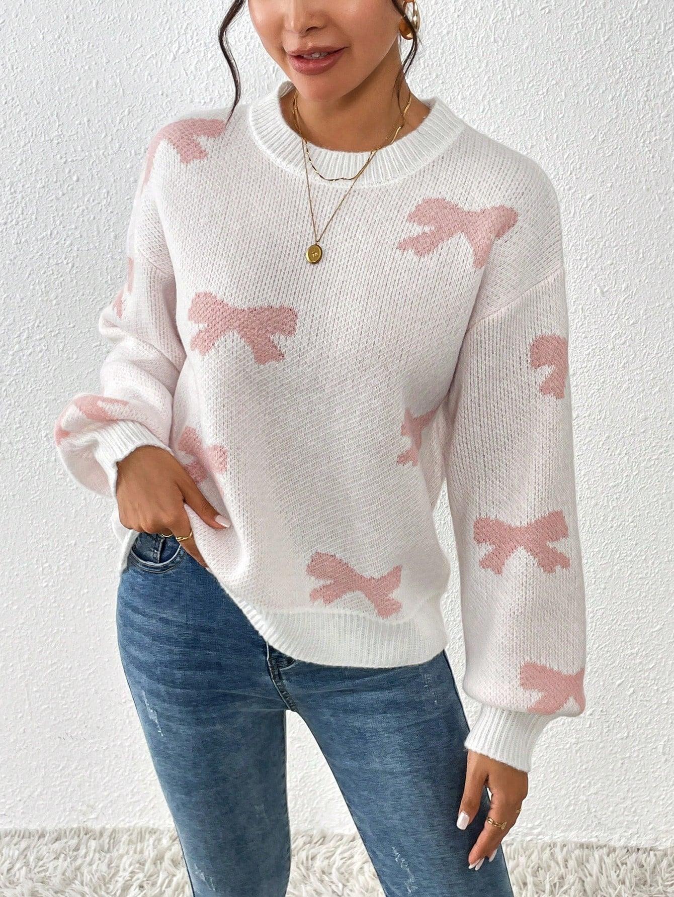 Close-up of a woman wearing a white crew neck sweater with pink bow print and blue jeans, showing the print detail