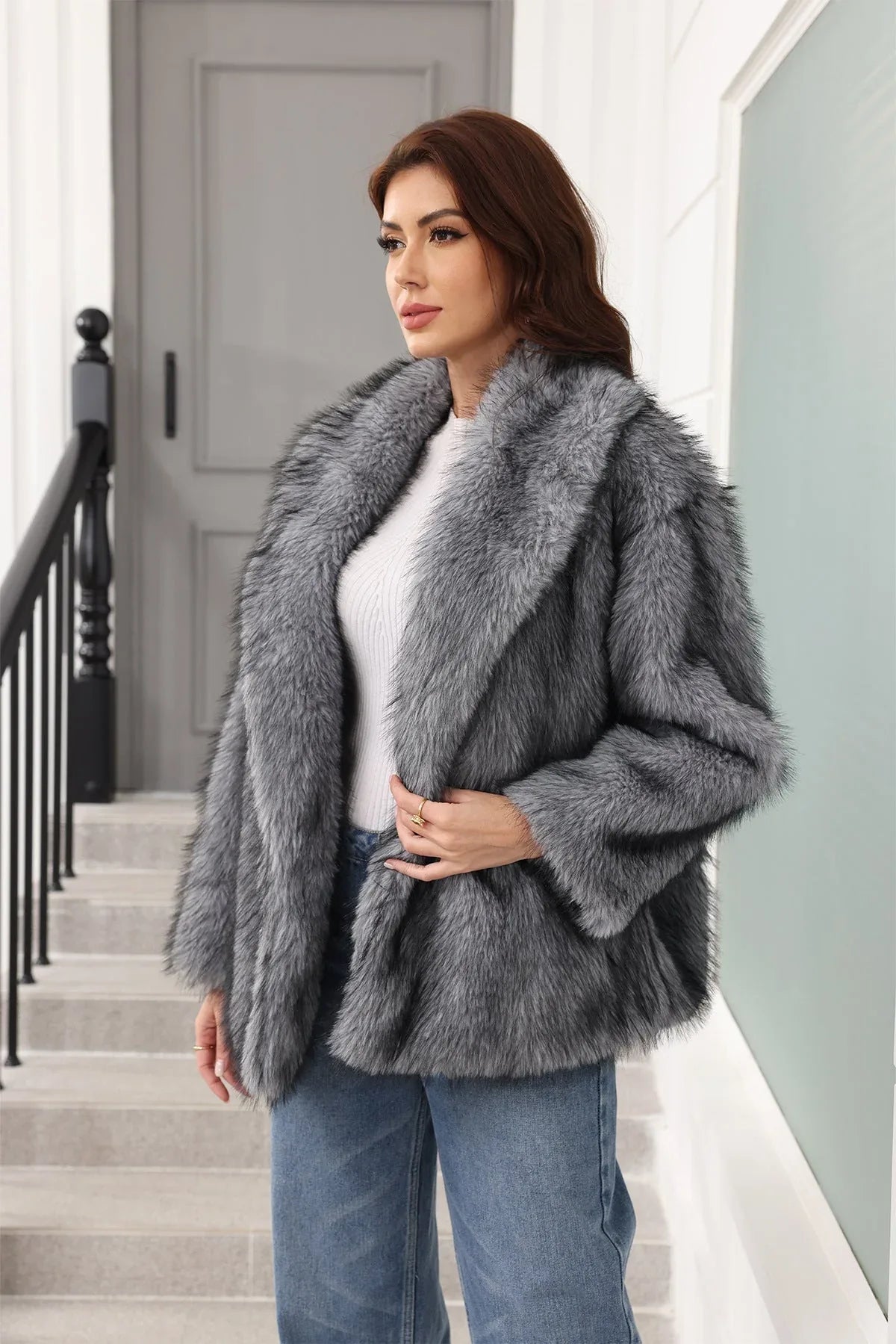 Woman in a grey faux fur jacket, posing with her hand on the lapel.