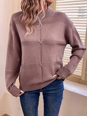 Woman in a mauve knit sweater with a mock neckline and long sleeves, hands tucked into pockets.