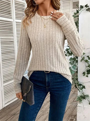 Woman wearing a cream ribbed long-sleeve crew neck top with dark wash jeans and holding a clutch