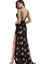 Back view of a woman in a black sequined evening gown with an open back and high leg slit.