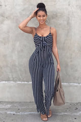 Woman wearing a navy and white striped jumpsuit with a tie-front detail and wide legs, posing outdoors.