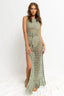Woman wearing a green crochet knit maxi dress with a high slit and fringe hem, front view.