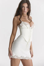 Woman wearing a white satin-like slip dress with lace trim and corset detail.