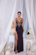 Full-length front view of a woman in a black satin gown with lace bodice and high slit.