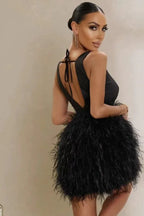 Rear view of a woman in a black sleeveless mini dress with a deep V-neckline and a feather skirt, showing the open back with tie detail.
