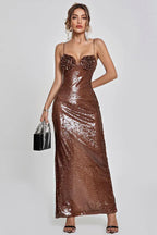 Woman in a shimmering bronze sequined evening gown with floral applique bust detail, spaghetti straps, and a floor-length hem.
