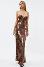 Full-length studio shot of a model wearing a flowing bronze sequined gown with floral bust detail.