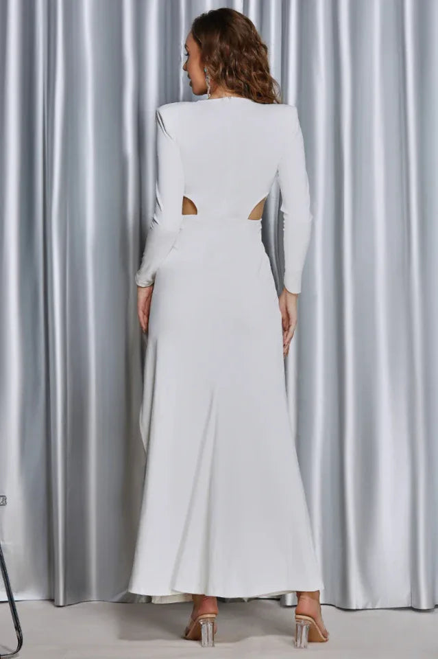 Back view of a woman in a white formal dress, showcasing the back cut-outs and flowing skirt.