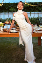 Woman in a white satin column gown with floral applique, posing at an outdoor table setting.