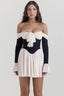 Woman wearing a black and ivory off-the-shoulder mini dress with a bow detail and flared sleeves.