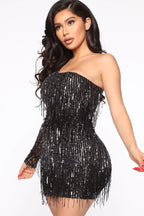 Close-up of a woman in a black sequined one-shoulder dress with fringe.
