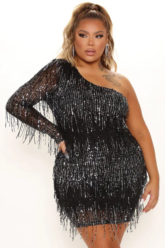 Model wearing a black sequined one-shoulder mini dress with fringe detailing.