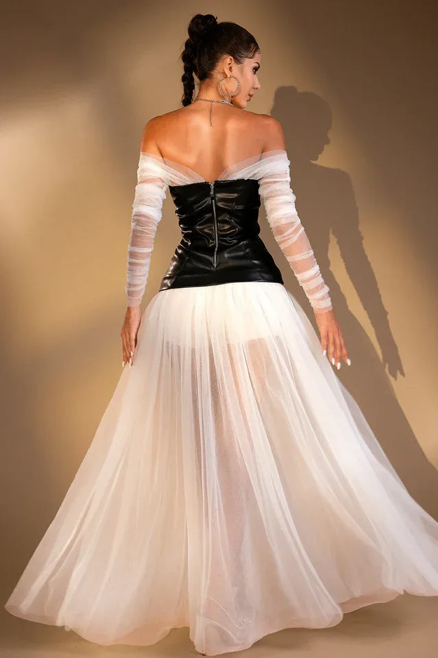 Rear view of a woman wearing a black off-the-shoulder corset top with sheer white long sleeves and a long white sheer tulle skirt.